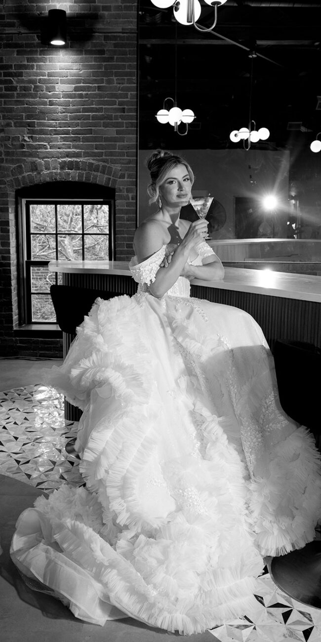 Bride posing with martini glass at bar