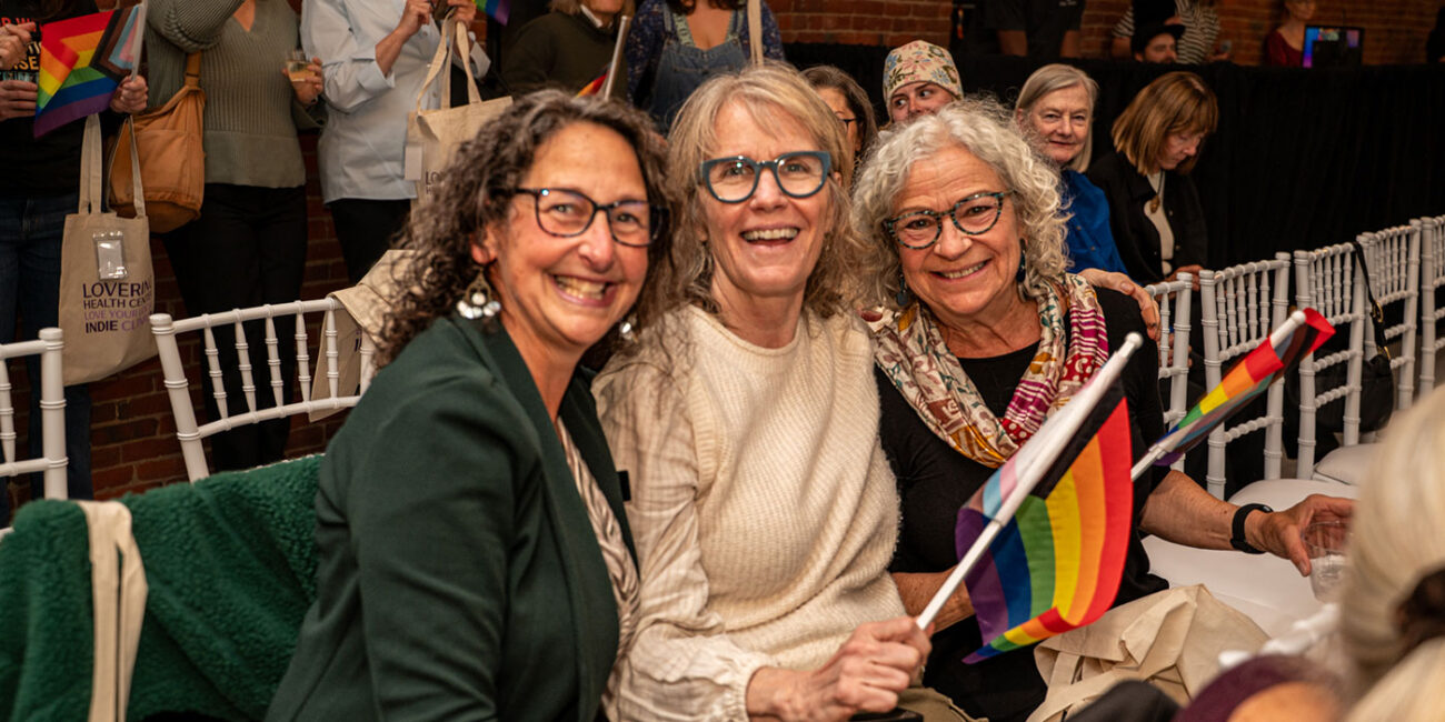 Group of women with rainbow flag at event LGBTQ+ supportive