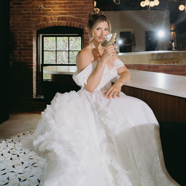 Bride posing at the bar with cocktail in hand