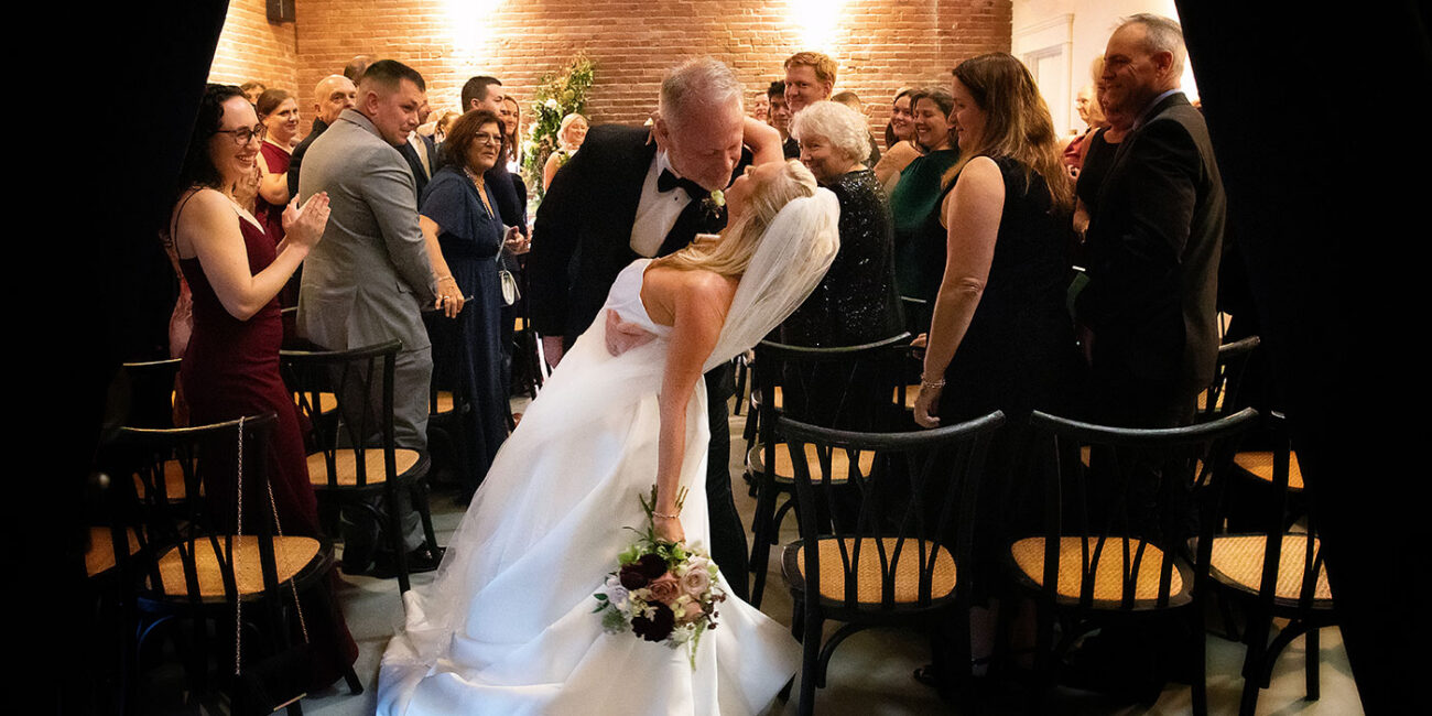 Groom kissing bride at the end of the aisle