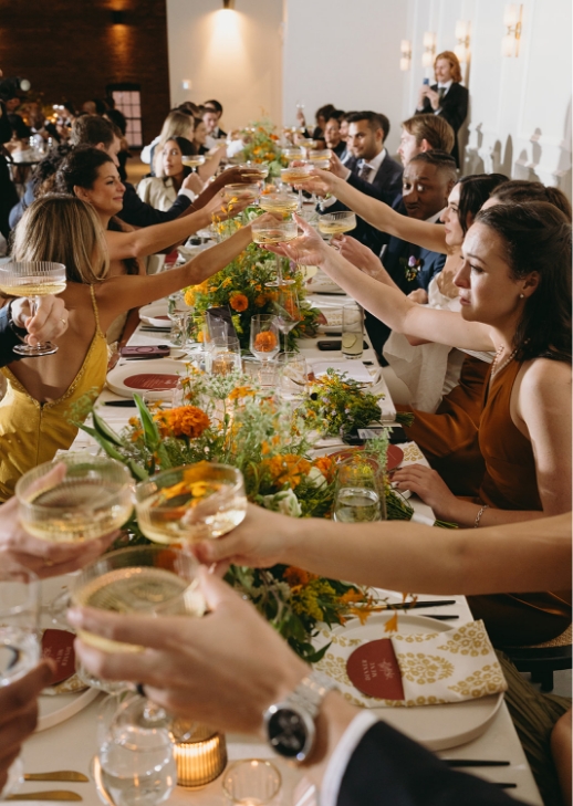 Guests cheers for a toast at long table