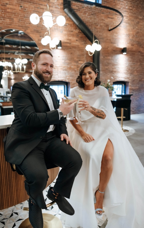 Elegant wedding couple sitting at bar cheers